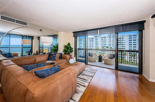 living room with a wall of windows, a water view, and hardwood / wood-style flooring