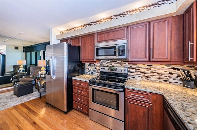 kitchen featuring appliances with stainless steel finishes, light wood-type flooring, light stone counters, and tasteful backsplash