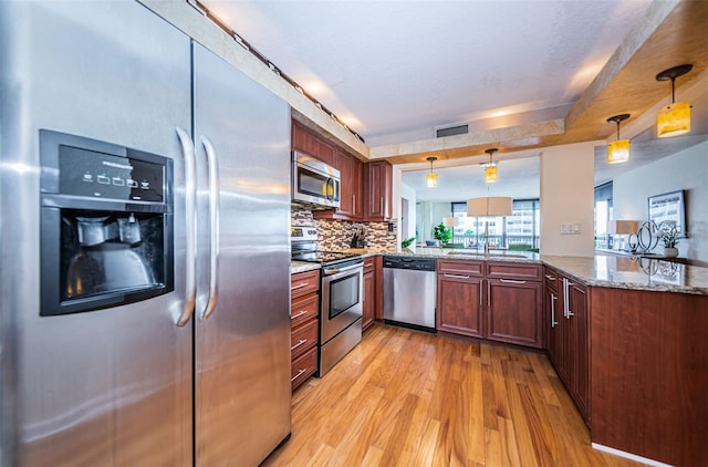 kitchen with stainless steel appliances, stone counters, hanging light fixtures, and kitchen peninsula