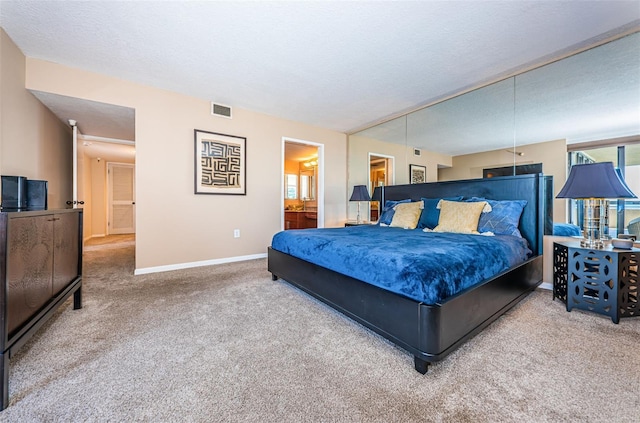 bedroom with ensuite bathroom, a textured ceiling, and carpet flooring