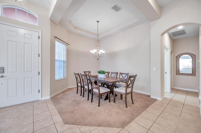 tiled dining room featuring a raised ceiling and a notable chandelier