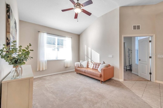 living room with ceiling fan, light tile patterned floors, and vaulted ceiling