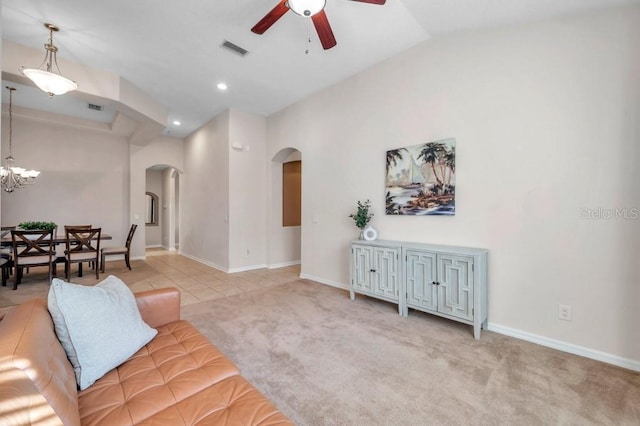 living room with ceiling fan with notable chandelier and light tile patterned floors