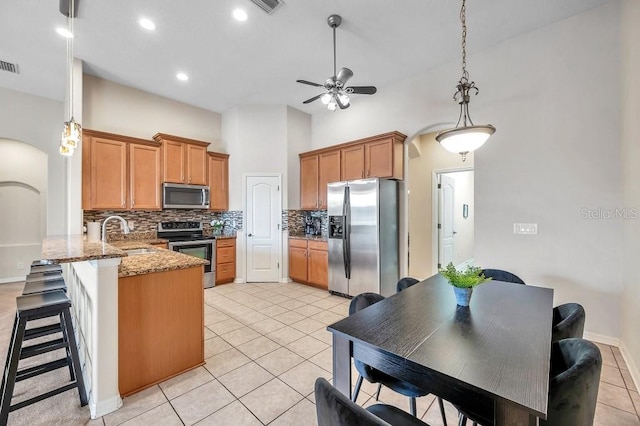 kitchen with sink, decorative backsplash, appliances with stainless steel finishes, light stone counters, and kitchen peninsula