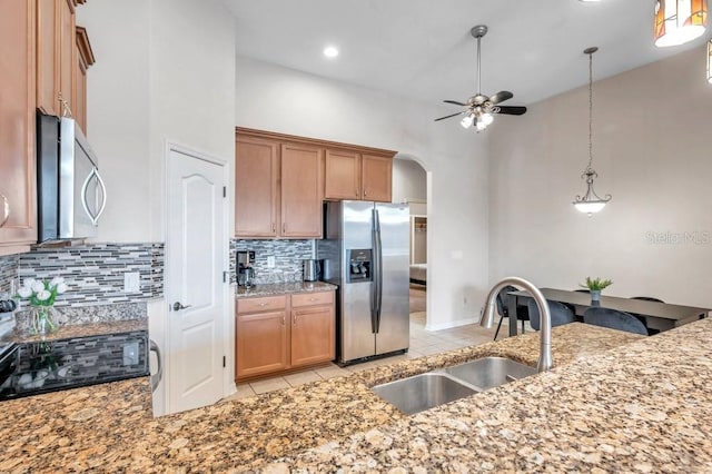 kitchen featuring sink, decorative backsplash, light tile patterned floors, a towering ceiling, and stainless steel appliances