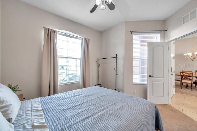 bedroom with light tile patterned floors and ceiling fan with notable chandelier