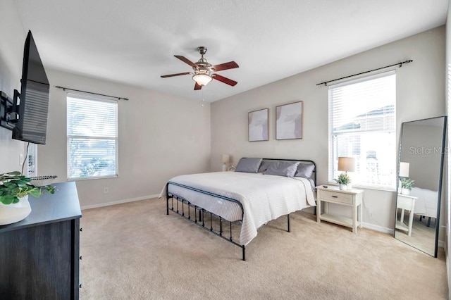 bedroom with multiple windows, light colored carpet, and ceiling fan