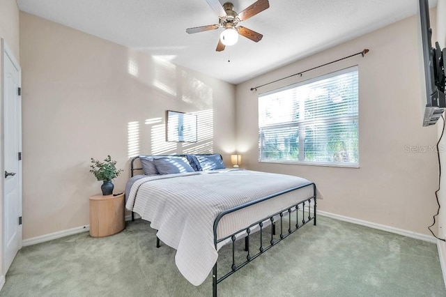 carpeted bedroom featuring multiple windows and ceiling fan