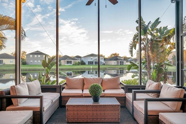 sunroom with ceiling fan and a water view