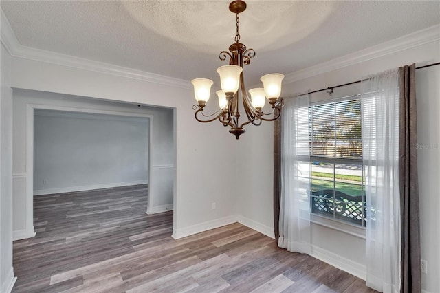 unfurnished dining area with wood-type flooring, ornamental molding, a textured ceiling, and a notable chandelier