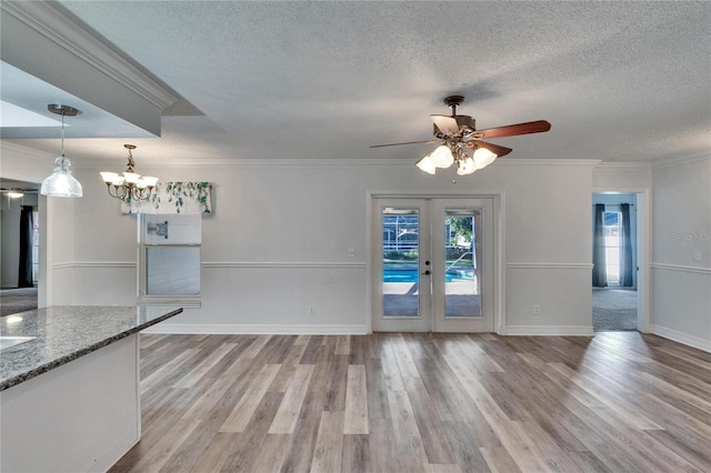 unfurnished living room featuring french doors, ceiling fan with notable chandelier, and ornamental molding