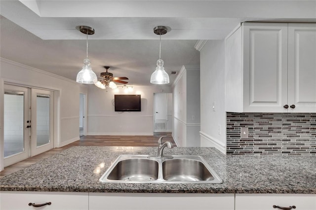 kitchen featuring white cabinets, french doors, decorative light fixtures, and sink