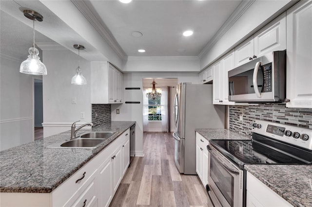 kitchen featuring appliances with stainless steel finishes, decorative light fixtures, white cabinetry, and sink