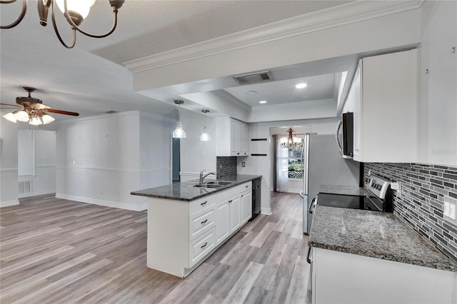 kitchen with appliances with stainless steel finishes, a tray ceiling, sink, decorative light fixtures, and white cabinets