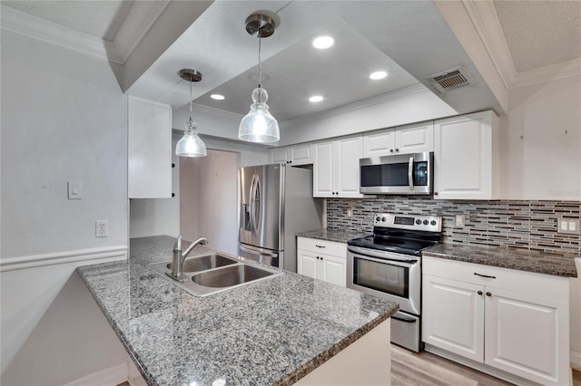 kitchen with kitchen peninsula, appliances with stainless steel finishes, white cabinets, and decorative light fixtures