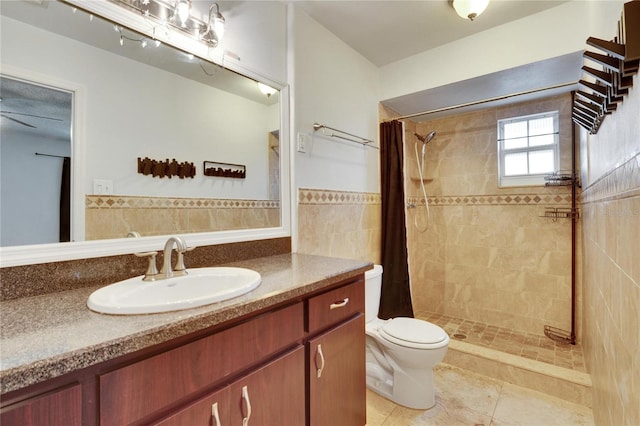 bathroom with a shower with shower curtain, vanity, toilet, and tile walls