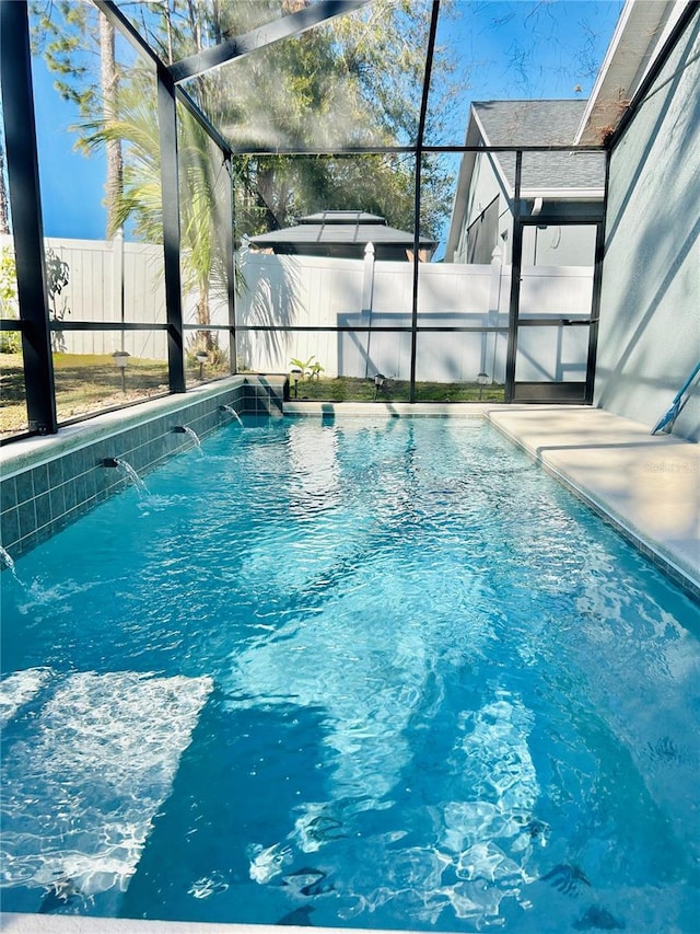 view of swimming pool featuring glass enclosure and pool water feature