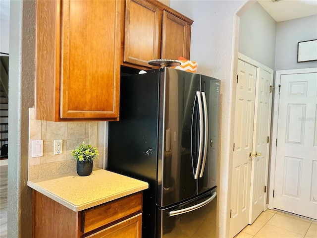 kitchen featuring backsplash, stainless steel fridge, and light tile patterned floors