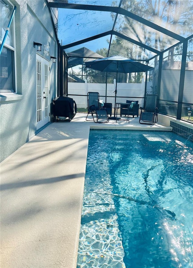 view of swimming pool featuring a lanai, a patio, and french doors