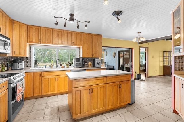 kitchen featuring light tile patterned flooring, a notable chandelier, backsplash, a kitchen island, and appliances with stainless steel finishes