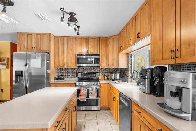 kitchen featuring sink, a kitchen island, backsplash, light tile patterned flooring, and appliances with stainless steel finishes