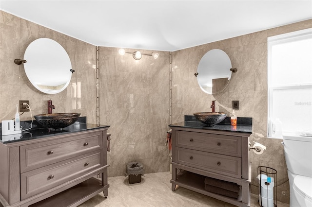 bathroom featuring tile patterned flooring, vanity, toilet, and tile walls