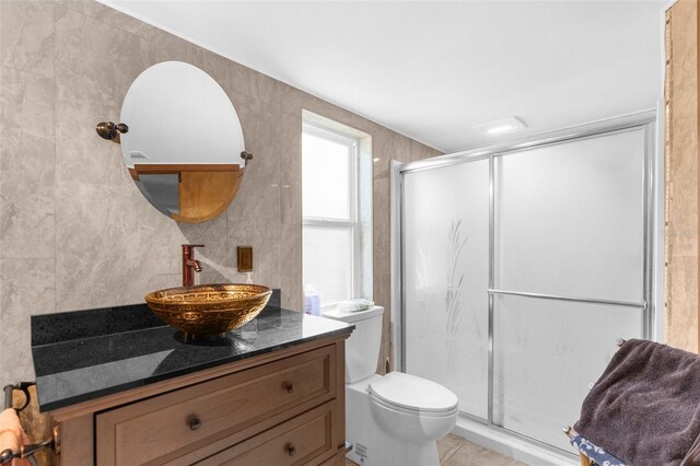 bathroom featuring walk in shower, vanity, toilet, and tile walls