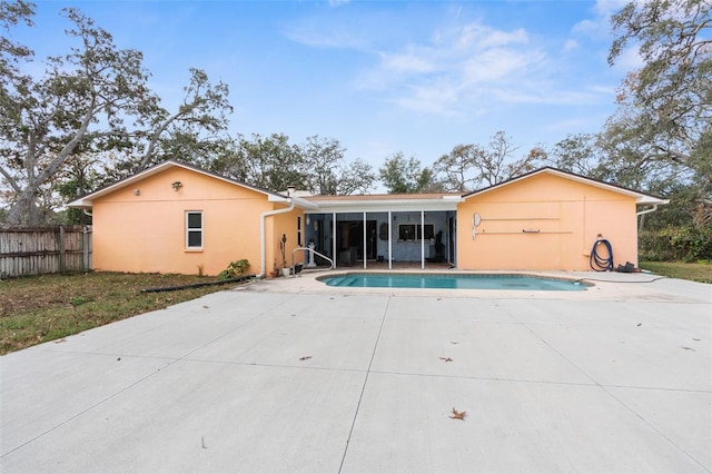 back of property with a fenced in pool, a sunroom, and a patio