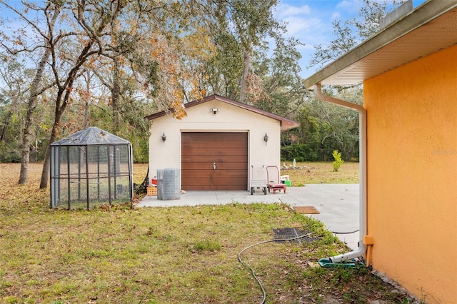 garage with a lawn and central AC unit