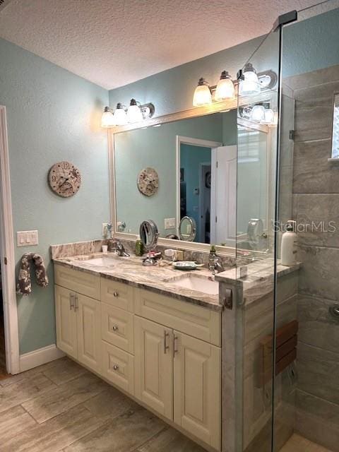 11021 Edge Park Dr, Hudson, FL 34667 - full bath featuring double vanity, wood finished floors, a sink, a textured ceiling, and a stall shower