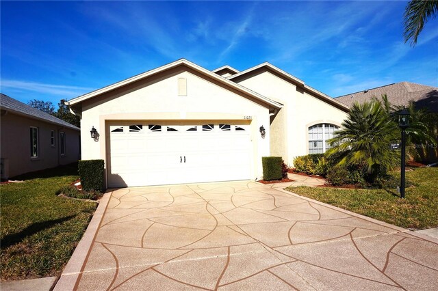 11021 Edge Park Dr, Hudson, FL 34667 - ranch-style home featuring stucco siding, concrete driveway, an attached garage, and a front lawn