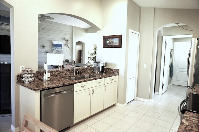 11021 Edge Park Dr, Hudson, FL 34667 - kitchen with appliances with stainless steel finishes, arched walkways, dark stone counters, light tile patterned floors, and a high ceiling