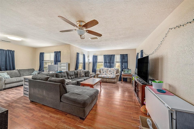 living room featuring a textured ceiling, ceiling fan, and dark wood-type flooring