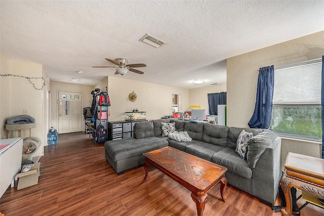 living room featuring a textured ceiling, dark hardwood / wood-style flooring, and ceiling fan