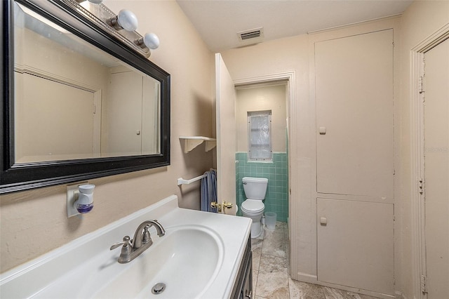 bathroom with vanity, tile walls, and toilet