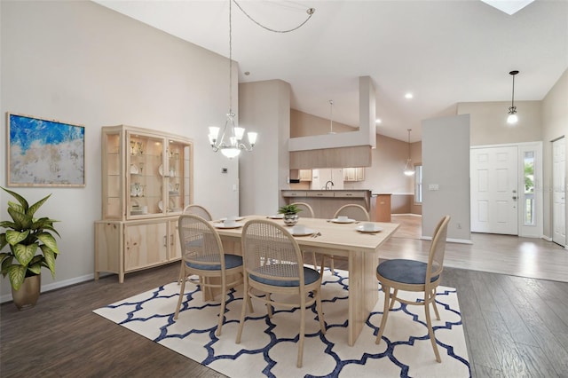 dining area with high vaulted ceiling, a notable chandelier, and dark hardwood / wood-style floors