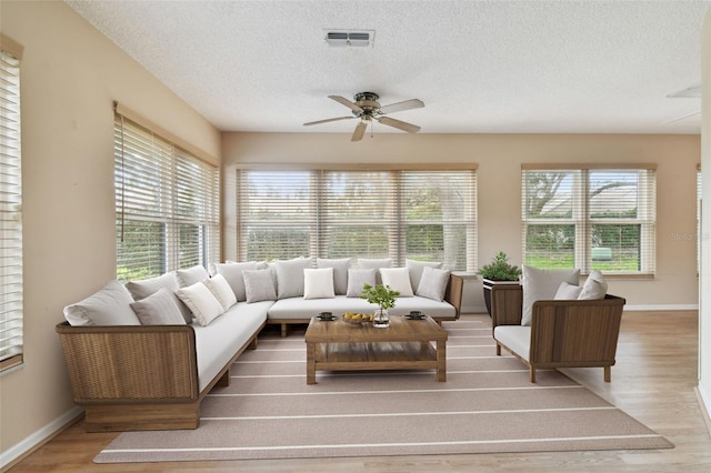 living room with a textured ceiling, ceiling fan, and wood-type flooring