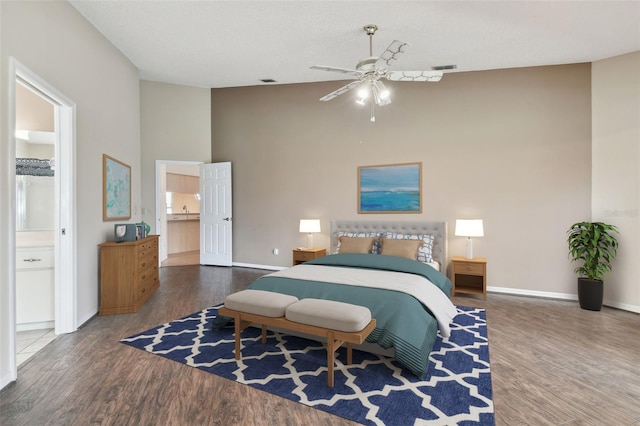 bedroom featuring a textured ceiling, a high ceiling, connected bathroom, dark hardwood / wood-style flooring, and ceiling fan