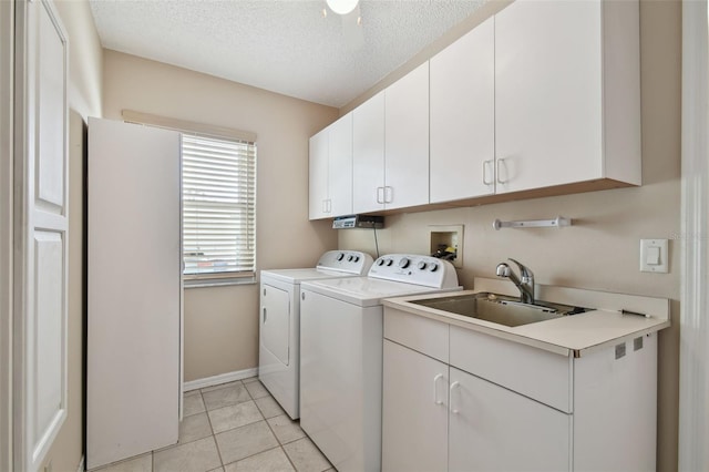 clothes washing area with sink, a textured ceiling, cabinets, independent washer and dryer, and light tile patterned flooring