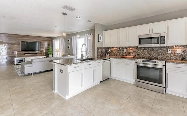 kitchen with kitchen peninsula, stainless steel appliances, white cabinets, and sink