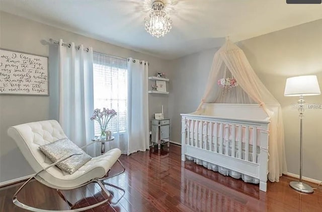 bedroom featuring a nursery area and dark hardwood / wood-style floors