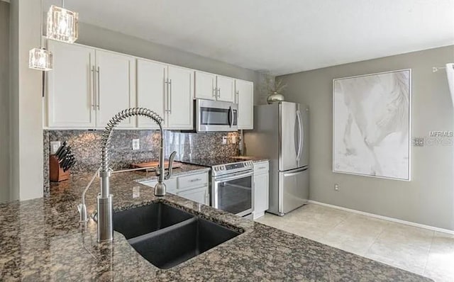 kitchen featuring white cabinetry, sink, dark stone counters, decorative backsplash, and appliances with stainless steel finishes