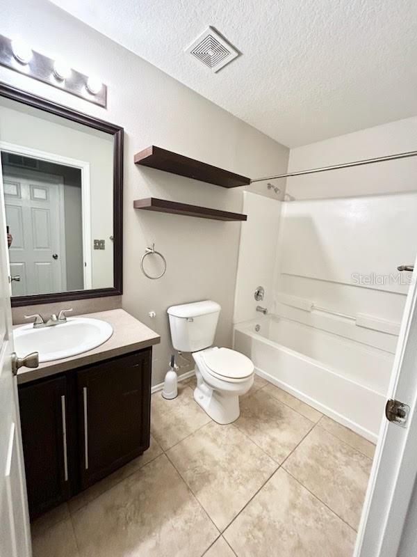 full bathroom with tile patterned floors, vanity, a textured ceiling, shower / bathing tub combination, and toilet