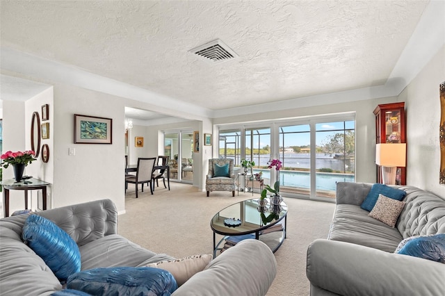 living room featuring a water view, light carpet, and a textured ceiling