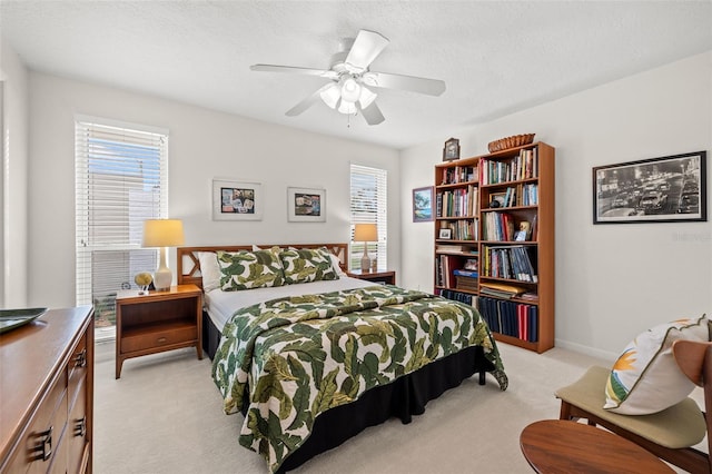 bedroom with ceiling fan, light carpet, and a textured ceiling