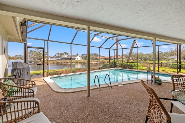 view of swimming pool with a patio, glass enclosure, and a water view