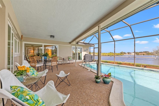 view of swimming pool featuring a lanai, a patio area, and a water view