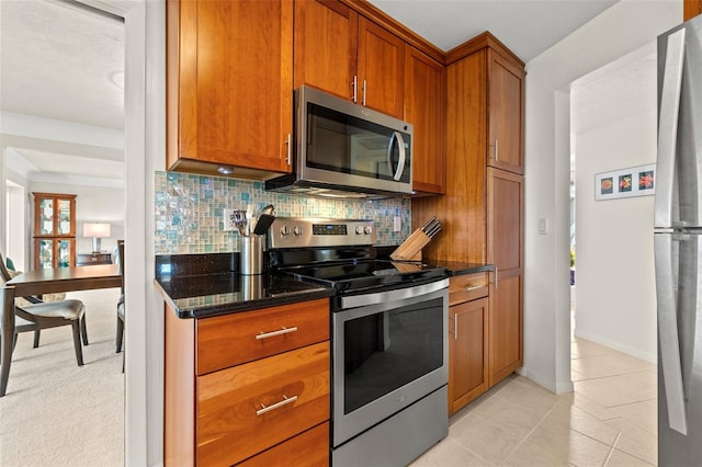 kitchen with backsplash, light tile patterned flooring, dark stone counters, and appliances with stainless steel finishes