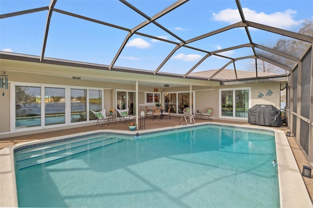 view of pool with a patio area, grilling area, and glass enclosure