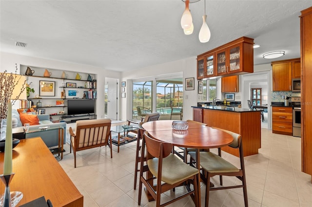 dining area featuring sink, a textured ceiling, and light tile patterned flooring